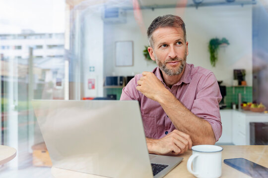 Confident professional in modern office working on laptop with coffee