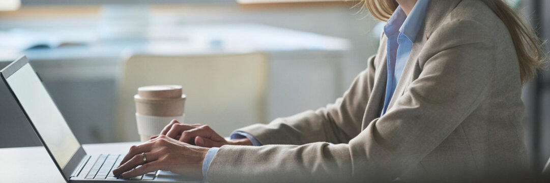 Business professional working on laptop with coffee at office desk