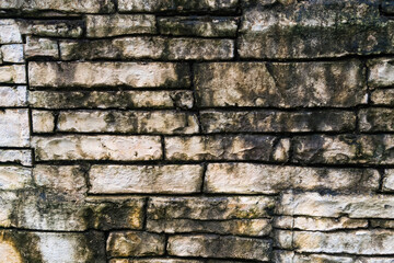 Close-up of an old stone wall with irregularly shaped stones featuring a natural and textured weathered surface