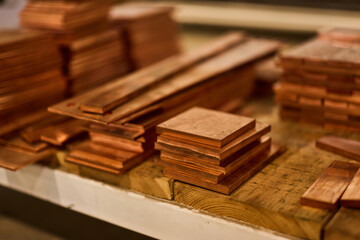 Stacks of Copper Plates on a Wooden Surface in a Workshop Setting