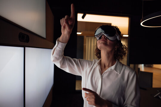 Businesswoman using VR glasses and interacting with digital screen in modern office