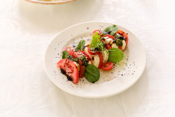 Fresh salad with tomatoes and greens served on white plate during lunch