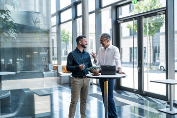 Two business professionals discussing work with tablet in modern office