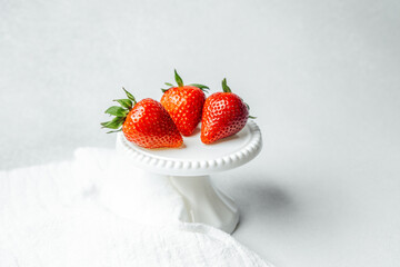 Fresh strawberries displayed on a small cake stand with a clean background