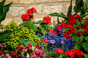 A vibrant arrangement of blooming flowers in front of a stone house, showcasing the beauty of a summer garden.