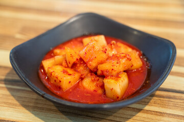 Spicy Korean Radish Kimchi in a Black Bowl