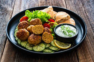 Greek cuisine - fried meatballs with tzatziki sauce and pita bread on wooden table