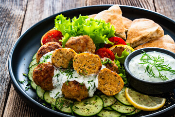 Greek cuisine - fried meatballs with tzatziki sauce and pita bread on wooden table