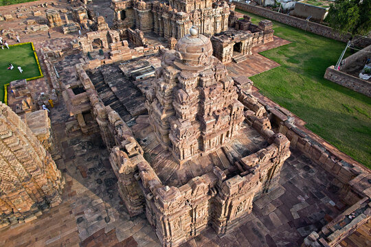 Aerial view of the Durga Temple complex with its intricate stone carvings and the surrounding lush green landscape, Aihole, Karnataka, India.