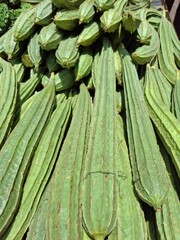 Obraz premium Stack of fresh green ridge gourds with ridged texture on display at a local market. A healthy, organic vegetable ideal for themes of farm produce, traditional cooking, and natural food