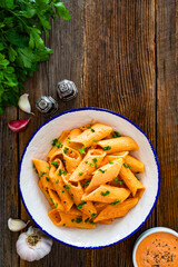 Creamy tomato and stracciatella pennone rigato noodles on wooden table