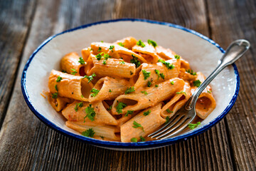 Creamy tomato and stracciatella pennone rigato noodles on wooden table