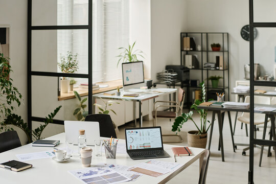 No people wide interior shot of modern office with laptops, computers and documents on desks, copy space