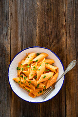 Creamy tomato and stracciatella pennone rigato noodles on wooden table