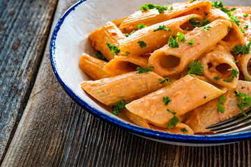 Creamy tomato and stracciatella pennone rigato noodles on wooden table