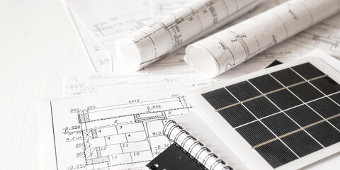 sustainable architecture tools and materials: blueprints, solar panel, wood textures, fabric swatches, and stones. Eco-friendly design, conscious construction and green innovation.