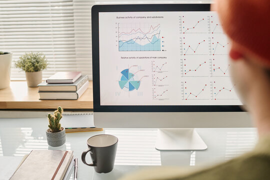Selective focus shot of unrecognizable man looking at desktop computer monitor with graphs and charts on screen