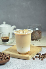 Ice coffee in a plastic cup with brown sugar and ice cubes and beans