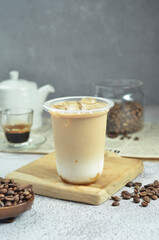 Ice coffee in a plastic cup with brown sugar and ice cubes and beans