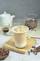 Ice coffee in a plastic cup with brown sugar and ice cubes and beans