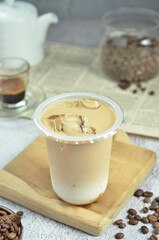 Ice coffee in a plastic cup with brown sugar and ice cubes and beans