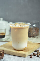 Ice coffee in a plastic cup with brown sugar and ice cubes and beans