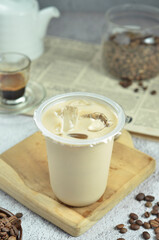 Ice coffee in a plastic cup with brown sugar and ice cubes and beans