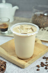 Ice coffee in a plastic cup with brown sugar and ice cubes and beans
