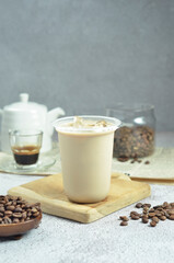 Ice coffee in a plastic cup with brown sugar and ice cubes and beans