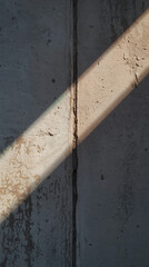 A photograph captures a rough concrete wall with visible seams and texture, intersected by a subtle rainbow spectrum beam of light, creating a sharp contrast between illuminated and shaded sections.