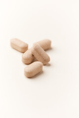 Lion’s mane mushrooms tablets that have beneficial effects on the body, especially the brain, heart, and intestines. Bright paper background. Soft focus. Close up. Copy space.	