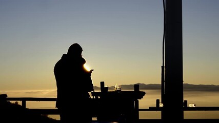 Silhouette couple enjoying scenic mountain sunset drinks at wooden bar balcony - Powered by Adobe