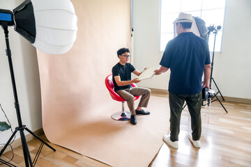 Photographer And Model Prepare For A Photoshoot, Reviewing Props Under Studio Lights