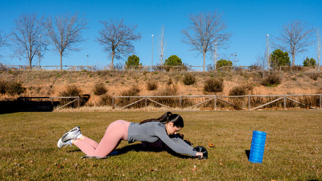 Female athlete performing outdoor ab rollout exercise