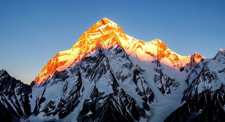 The sun's golden rays illuminate the snow-covered summit of a majestic mountain at sunrise or sunset k2