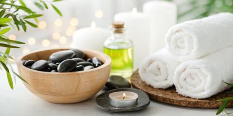 Business background.Minimalist spa concept with rolled white towels, black massage stones, scented candles, and herbal oils in a calm and refreshing atmosphere