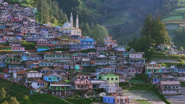 Aerial view of dense residential houses stacked along a green hillside, with with colorful houses standing in the middle of a rural Asian village. Nepal Van Java, Mount Sumbing, Indonesia.