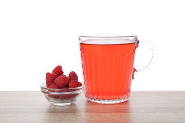 Aromatic raspberry tea in glass cup and berries on wooden table against white background