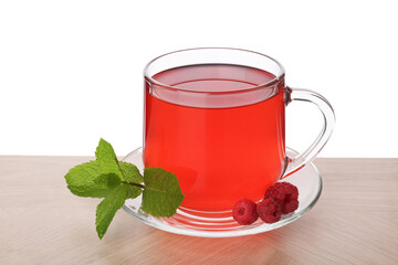 Aromatic raspberry tea in glass cup, berries and green leaves on wooden table against white background