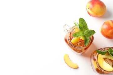 Refreshing iced peach tea with mint in mason jars and fresh fruits on white table, flat lay. Space for text