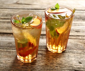Refreshing iced peach tea in glasses on wooden table, closeup