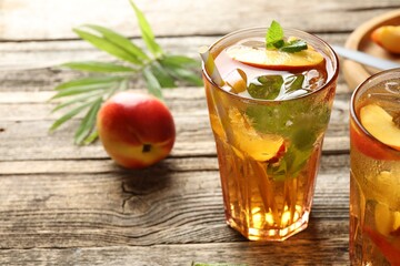 Refreshing iced peach tea in glasses and fresh fruits on wooden table, closeup