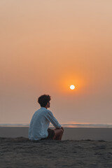 man sits on ground during sunset his hands resting on his knees embodying determination and calm