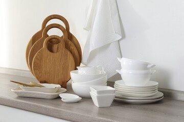Different clean white dishware and wooden cutting boards on counter in kitchen