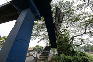 Drivers pass beside a damaged pedestrian bridge.