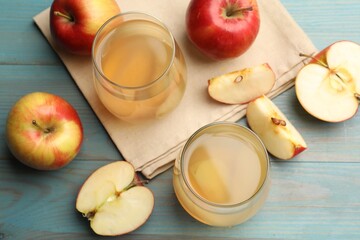 Tasty compot in glasses and fresh apples on light blue wooden table, flat lay