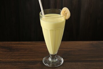Tasty banana milkshake in glass on wooden table, closeup