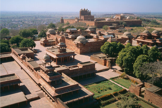 Aerial view of red sandstone buildings and courtyards under a clear sky, showcasing the architectural heritage of Fatehpur Sikri, Uttar Pradesh, India.