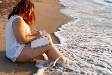 Woman writing in notebook at beach enjoying summer vacation