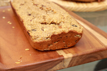 Homemade oatmeal bread with nuts and raisins displayed on a wooden board 